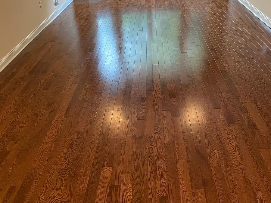 Refinished hardwood floor in a long room with a bay window