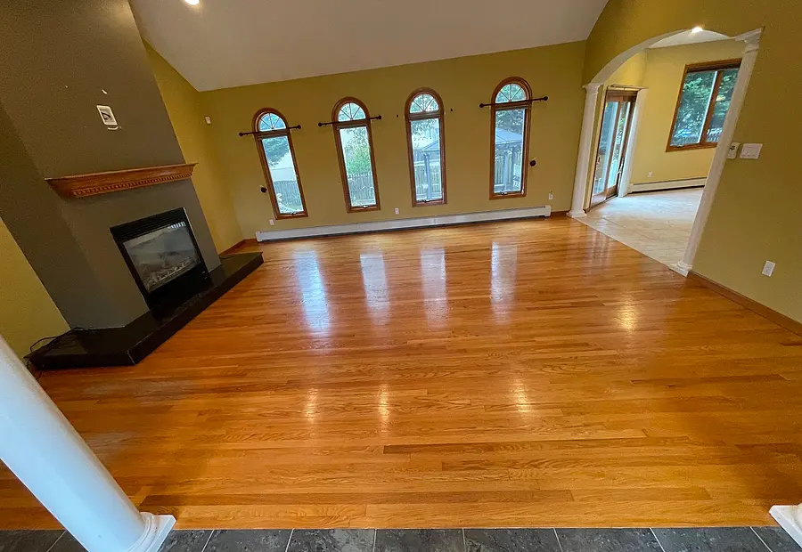 Refinished hardwood floor in a living room with a fireplace and arched windows